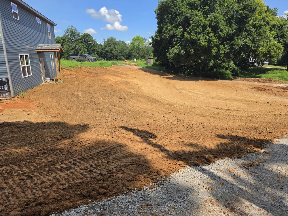 A wide, freshly graded yard beside a house, leveled smooth and ready for seed.